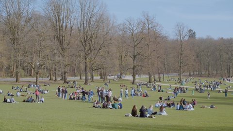 Brussels , Belgium - 03 27 2021: People relax on the green lawn in Bois de La Cambre park