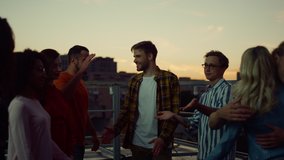 Beautiful people giving high five each other at a rooftop event. Young friends enjoying time together at roof party. Happy guys and girls hugging while evening meeting outdoors.  - Powered by Shutterstock - Get 15% off with code: PIKWIZARD15