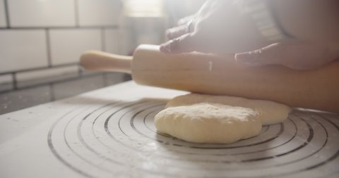 Slow motion Close up hands of bakery Chef preparing flour and kneading roll out dough with a rolling pin on the table, Ingredients and preparation stages for cooking making bread cake at kitchen