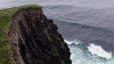 Aerial view of Waves crashing on cliffs,dark rocks,irish ocean,rough sea,ocean wave storm,storm shore,ocean waves.clouds and waves on the sea.Ireland cliffs,seagulls fly,summer.Ireland