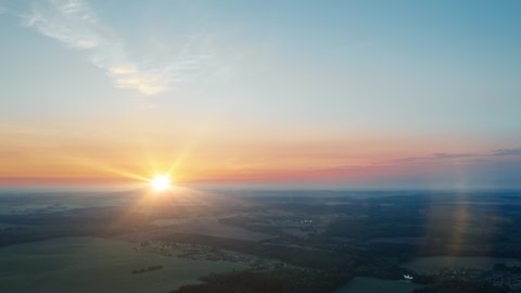 Aerial time-lapse hyperlapse summer morning in forest. Bright sun rises over wonderful woodland. Drone flight over trees. Beautiful dawn. Idyllic landscape sunrise. Sun beams in moving clouds