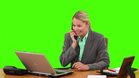 Chroma-key footage of blond businesswoman talking on the phone at her desk