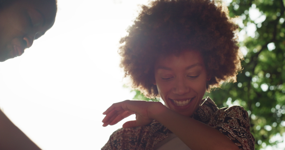 Portrait of Black Stylish Female Teenager Dancing With her Friends Outdoors in a Park. Cheerful Happy Girl with Curly Hair Having Fan and Enjoying Summer. Energetic Young Woman Being Carefree