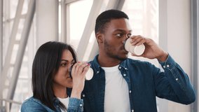 Black Tourists Couple Drinking Coffee From Paper Cups Waiting For Their Flight Standing In Airport Indoors, Looking Aside. Transportation And Tourism, Traveling Concept. Tracking Shot