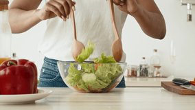 Black Millennial Woman Cooking Mixing Salad Ingredients In Bowl Preparing Dinner Standing In Modern Kitchen At Home. Healthy Nutrition And Food, Weight Loss Recipes Concept. Tracking Shot