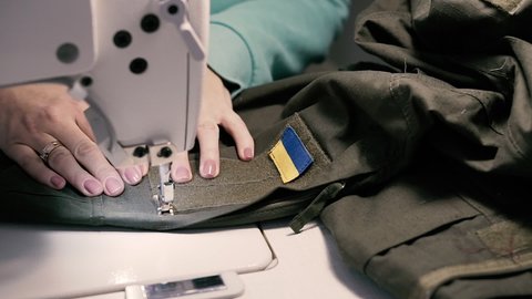 Sew. A woman sews a Ukrainian military uniform on a sewing machine. Close-up.