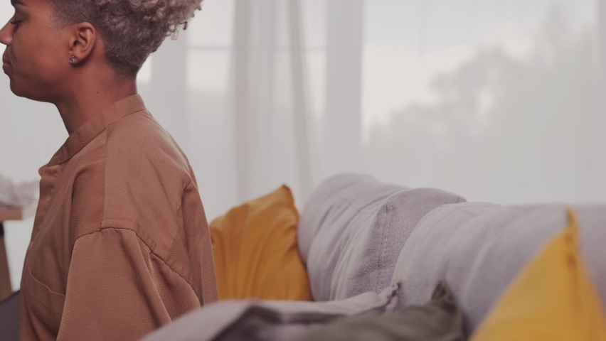 Close up tranquil peaceful young African American woman leaning on comfortable sofa, daydreaming sleeping resting alone in living room, meditating or having pleasant dreams on weekend.