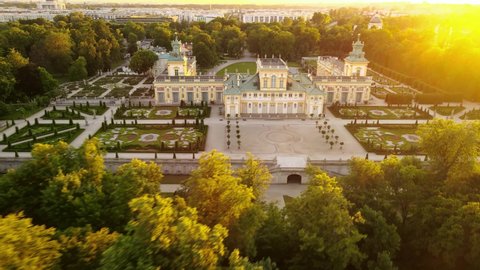 Drone aerial top view of the ancient royal castle palace with a park and a pond during a golden sunset. Historical place, tourist point spots of the city. Sunset, city on the horizon.
