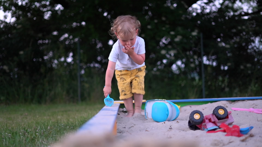 Cute blond kid playing in the sandbox with plastic toys alone. Happy childhood, children's leisure Royalty-Free Stock Footage #1074597713