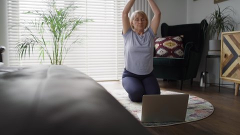 Tracking video of active senior woman meditating on exercise mat.  Shot with RED helium camera.