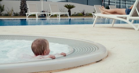 Young little baby girl jumping and having fun in outdoors hot tub on vacations