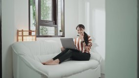 Asian woman sit on sofa at home wear wireless headphones put laptop on laps talk on video conferencing, lead business remotely, share knowledge via videocall. Formal informal virtual meeting concept