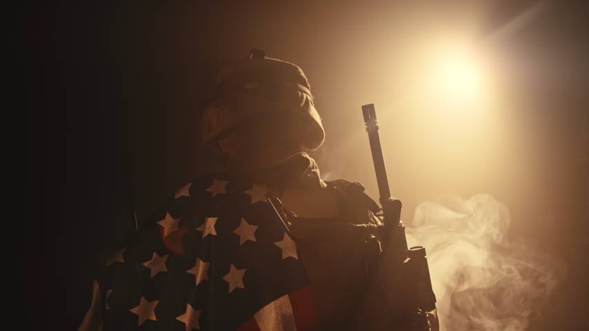 soldier standing with his back to us in the dark holding USA national flag Royalty-Free Stock Footage #1074610778
