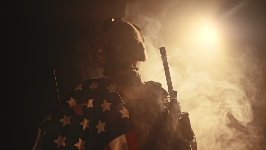 soldier standing with his back to us in the dark holding USA national flag Royalty-Free Stock Footage #1074610778