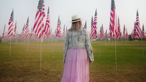 Camera following young woman walking by the impressive September 11th Memorial display at Malibu, California, USA. Memorial park with American flags in memory of the terror attacks on September 11