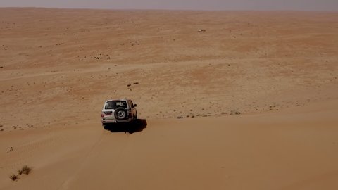 Sweeping view of Off-Road Desert Cruiser going down a steep Omani Dune - Aerial Panoramic Tracking shot