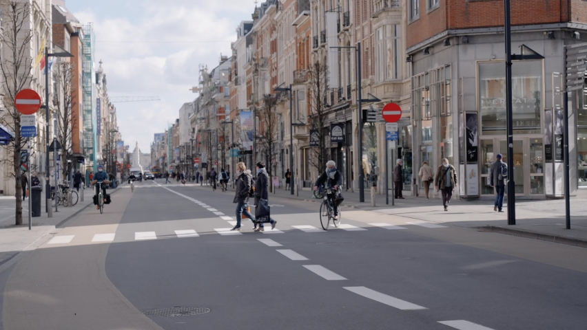 Leuven , Belgium - 03 23 2021: Masked people ride bicycles in the city centre of Leuven, Belgium. Coronavirus pandemic continues