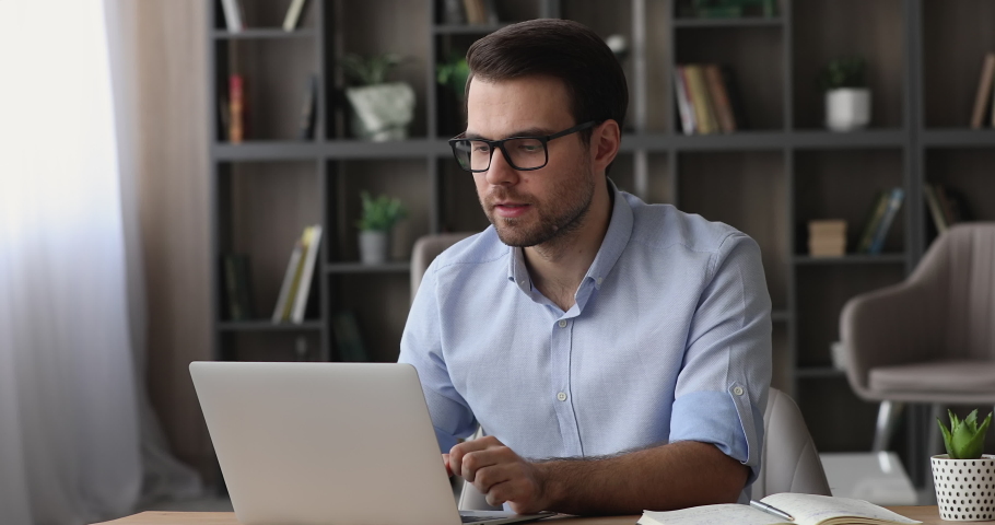 Bad-tempered man sit at desk stressing out while work on laptop, having difficulties with device, blogger read unpleasant comment text rude answer to subscriber, modern tech, nervous breakdown concept Royalty-Free Stock Footage #1074628679