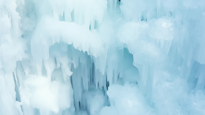 Aerial close up shot of an ice slope bumps, ridges, and icicles by which climbing up man using traction ice tool technique Royalty-Free Stock Footage #1074628988
