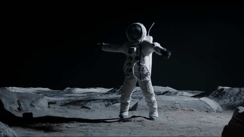 Male astronaut performing moonwalk dance move on a Moon surface. Shot with 2x anamorphic lens Royalty-Free Stock Footage #1074629114