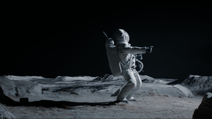 Male astronaut performing moonwalk dance move on a Moon surface. Shot with 2x anamorphic lens