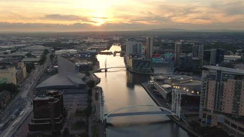 Manchester, England, 01-08-2020: Salford quays MediaCityUK aerial view drone flying forward over canal ship at sunset dusk
