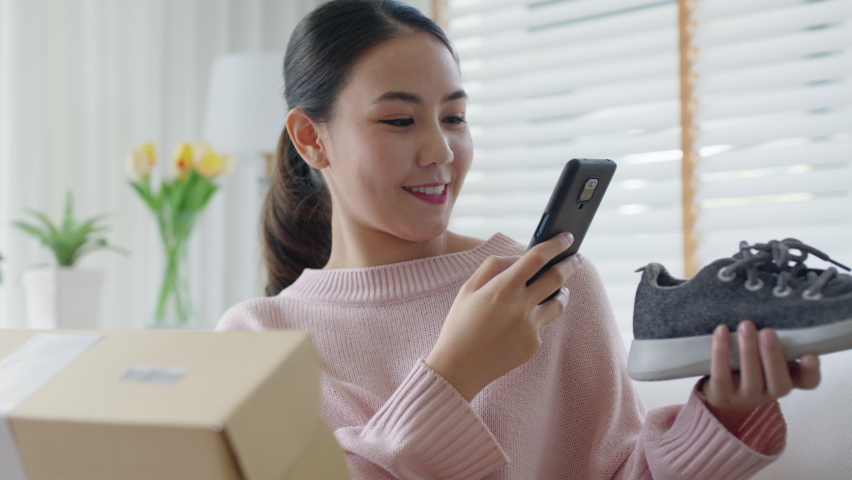 Young asia people happy teen girl smile unbox open gift new shoe buy order from online store shop take photo shoot camera show post social media app blog vlog share sit relax at home sofa couch. | Shutterstock HD Video #1074637604