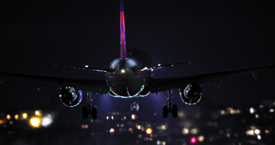 Night scene airport 4K footage. Close up back view of descending airplane. International airport terminal with signal lights on. Tourism background with plane touching down the runway, United States Royalty-Free Stock Footage #1074637607
