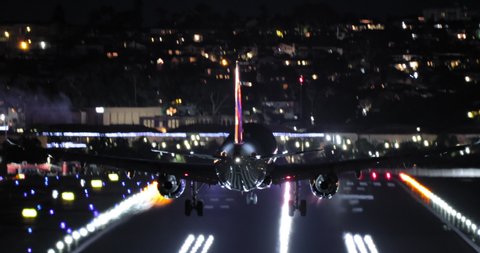 Night scene airport 4K footage. Close up back view of descending airplane. International airport terminal with signal lights on. Tourism background with plane touching down the runway, United States