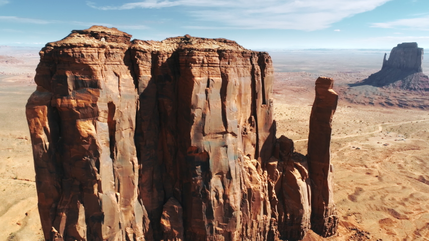 Cinematic close up view on Mitten Butte - famous steep red rock in Monument Valley, Navajo Indian reservation, Arizona, Utah, USA. Beautiful mountains aerial on summer sunny day. Travel background