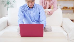 Asian senior couple watching a laptop PC in the room.
