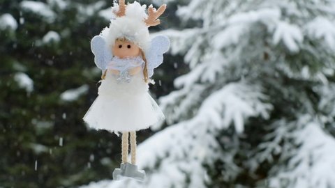 Winter angel on a snowy tree.Christmas decorative angel. Snowfall.