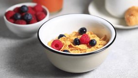 Milk is poured into a bowl with cornflakes and berries. Dry breakfast