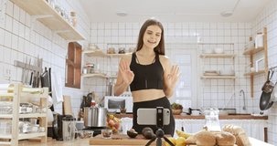 Beautiful young fit sports girl broadcasting online live video teaching healthy food cooking in kitchen at home