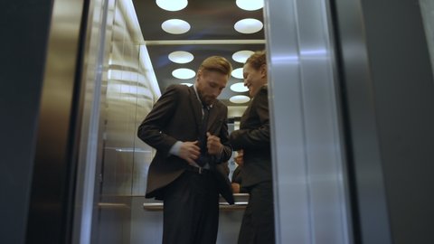 Elevator door opening, embarrassed couple of colleagues exiting, caught flirting