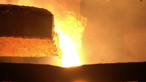 From the blast furnace, molten liquid metal is poured down the chute into the crucible, close-up, steel production.