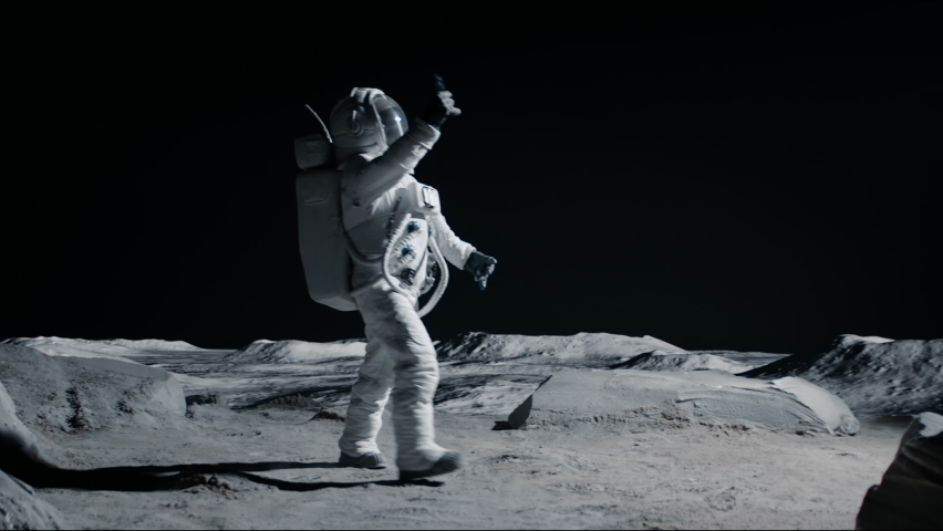 Astronaut searching for cellular or wi-fi signal while walking on Moon surface. Shot with 2x anamorphic lens Royalty-Free Stock Footage #1074659966