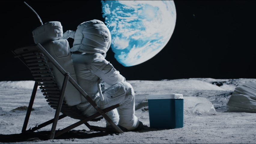 Back view of lunar astronaut opens a beer bottle while resting in a beach chair on Moon surface, enjoying view of Earth. Shot with 2x anamorphic lens Royalty-Free Stock Footage #1074659972
