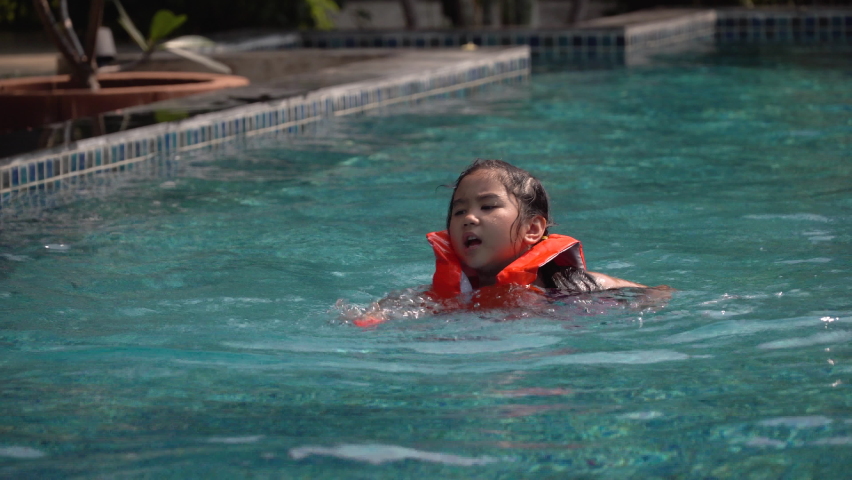 asian girl in life jacket  Practice Swimming in the pool 