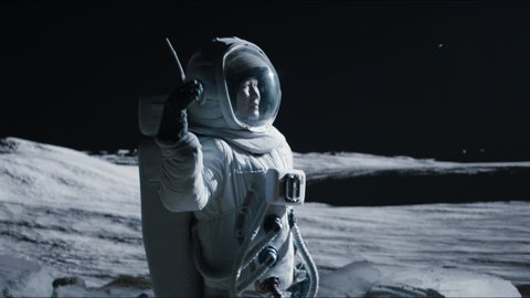 MID JIB Portrait of Asian lunar astronaut opens his visor while exploring Moon surface. Shot with 2x anamorphic lens