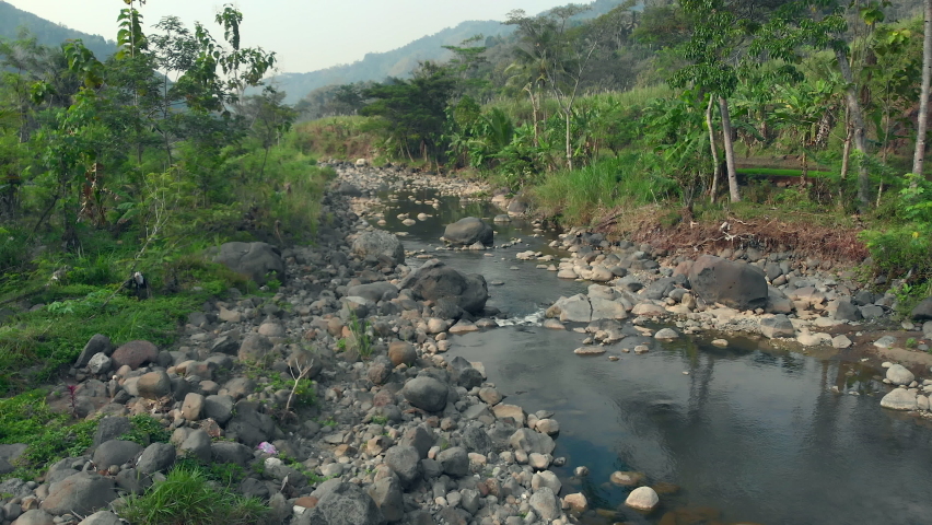 Riverside landscape aerial view with volcanic rocks boulder and water flow
