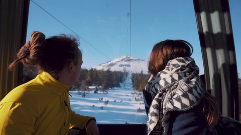 krkonose , Czech Republic - 01 08 2021: Young couple sits in gondola ski lift watching beautiful snowy landscape outside