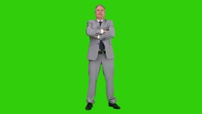 Elderly businessman in  a gray suit looking at the camera against a green screen