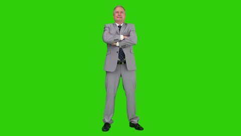 Elderly businessman in  a gray suit looking at the camera against a green screen