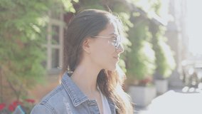 Great weather. Portrait view of the brunette cute woman wearing glasses standing at the summer street and looking at the camera while walking and enjoying of the walking. Stock video
