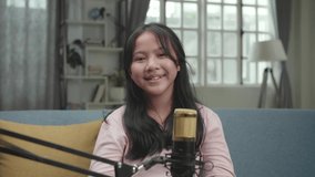 Asian Girl Vlogger With Microphone Smiling. The Child Is Broadcasting Live On The Internet.
