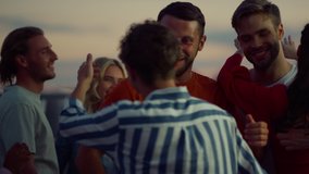 Cheerful friends greeting each other at rooftop evening party. Beautiful people hugging while meeting outdoors. Young buddies feeling happy together outside. Friendship concept. - Powered by Shutterstock - Get 15% off with code: PIKWIZARD15
