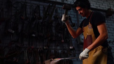 slow motion video of italian brunette man blacksmith working in the workshop