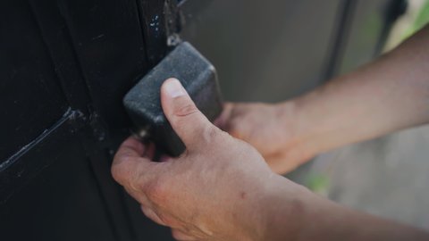 A man closes the gate of a car garage. Shooting hands with keys close-up