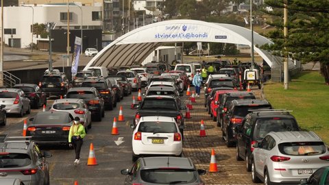 SYDNEY, NSW, AUSTRALIA, JUNE 20 2021. Staff walk between cars lined up at Covid testing drive through.